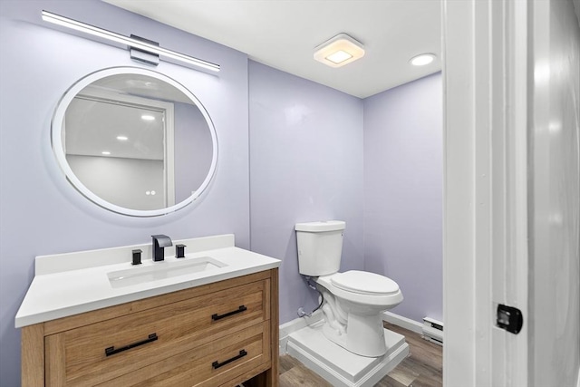 bathroom with baseboard heating, hardwood / wood-style floors, vanity, and toilet