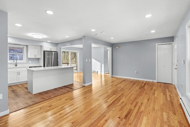 kitchen featuring white cabinets, stainless steel fridge, light wood-type flooring, and sink