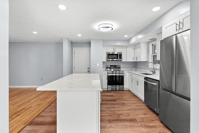 kitchen with hardwood / wood-style flooring, a center island, white cabinetry, and appliances with stainless steel finishes