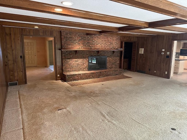 96 Wild Grove Ln, Longmeadow, MA 01106 - unfurnished living room featuring wood walls, beamed ceiling, carpet floors, and a brick fireplace