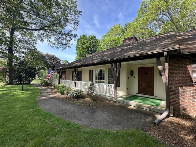 96 Wild Grove Ln, Longmeadow, MA 01106 - view of front of house with a front yard, a porch, a chimney, brick siding, and a shingled roof