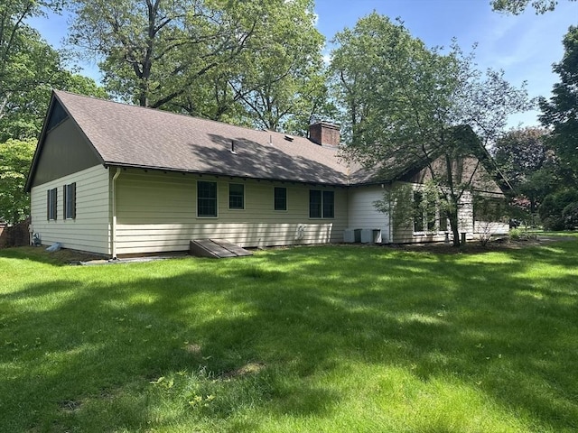 96 Wild Grove Ln, Longmeadow, MA 01106 - rear view of house with a chimney, a lawn, a shingled roof, and central AC unit
