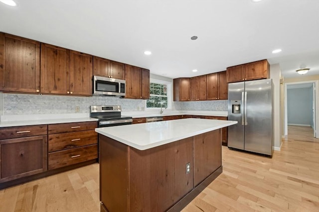 kitchen featuring appliances with stainless steel finishes, a center island, sink, and light wood-type flooring