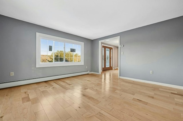 spare room with light wood-type flooring and a baseboard heating unit