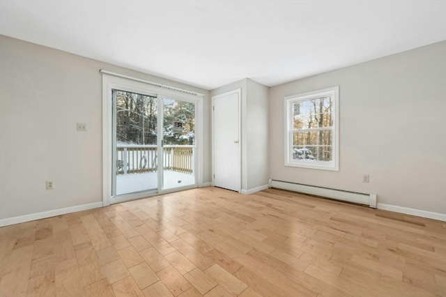 spare room featuring baseboard heating and light hardwood / wood-style flooring