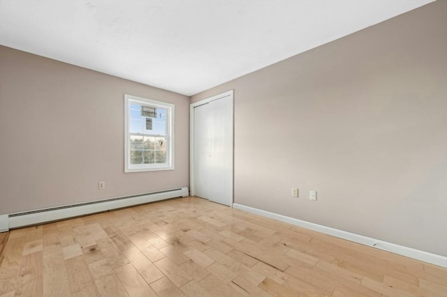 unfurnished room with baseboard heating and light hardwood / wood-style flooring