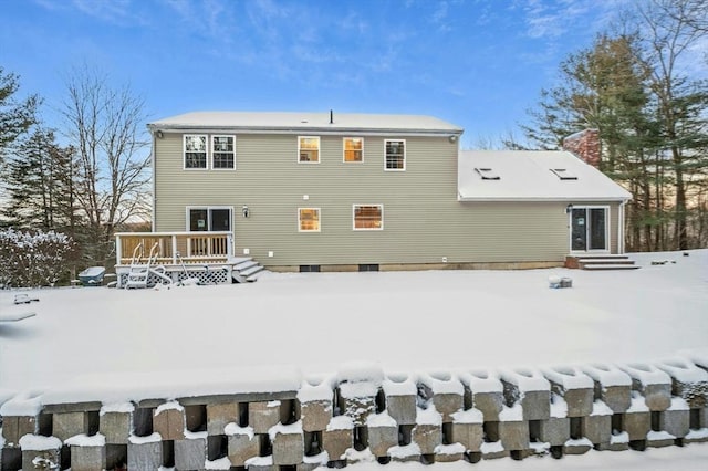 snow covered back of property with a wooden deck