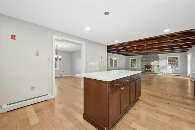 kitchen featuring baseboard heating, a stone fireplace, a kitchen island, and light wood-type flooring