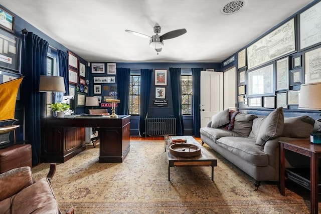 home office featuring ceiling fan, a healthy amount of sunlight, radiator, and wood-type flooring