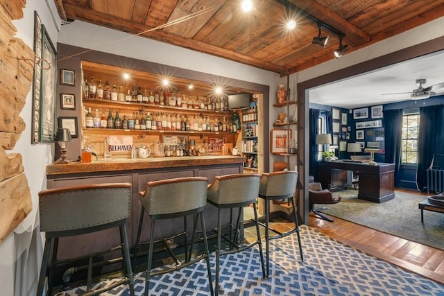 bar featuring dark hardwood / wood-style flooring, ceiling fan, track lighting, wooden ceiling, and built in shelves