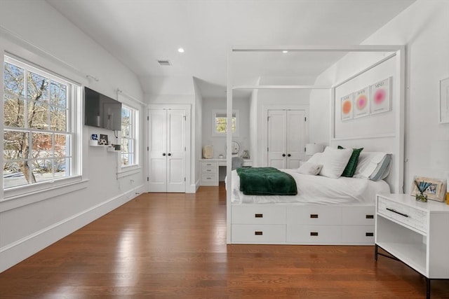 bedroom with dark hardwood / wood-style flooring and multiple closets