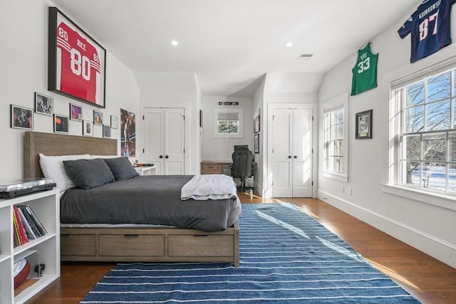 bedroom with dark hardwood / wood-style flooring and multiple closets