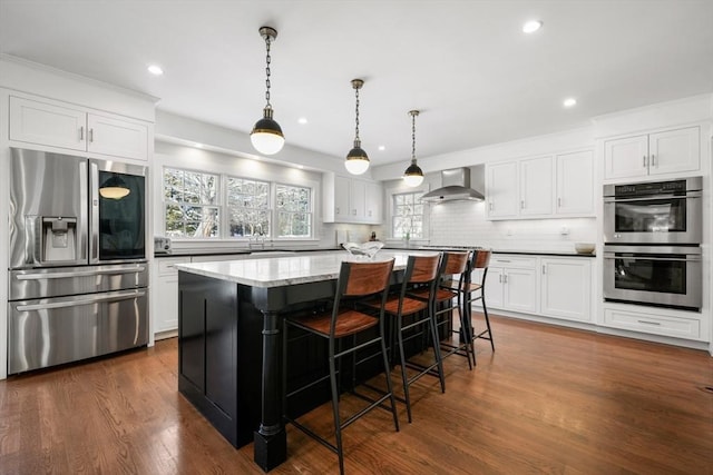 kitchen with stainless steel appliances, white cabinetry, pendant lighting, and wall chimney exhaust hood