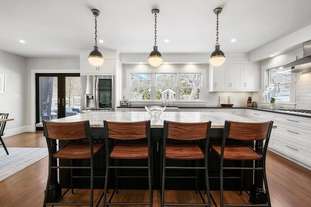 kitchen with white cabinetry, a breakfast bar, dark stone counters, and stainless steel fridge with ice dispenser