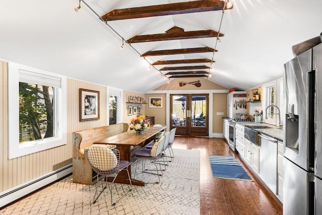 dining room with sink, vaulted ceiling with beams, light hardwood / wood-style floors, baseboard heating, and french doors