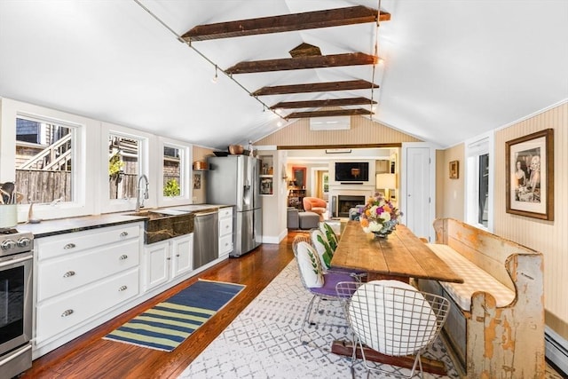 kitchen featuring lofted ceiling with beams, white cabinetry, a baseboard radiator, stainless steel appliances, and dark wood-type flooring