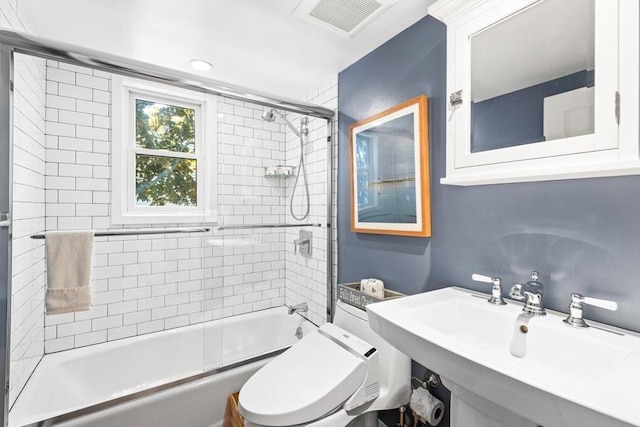 full bathroom featuring sink, enclosed tub / shower combo, and toilet