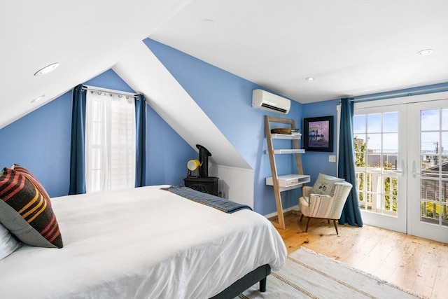 bedroom with lofted ceiling, access to exterior, light hardwood / wood-style floors, french doors, and an AC wall unit