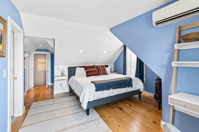 bedroom featuring lofted ceiling, a wall mounted air conditioner, and light wood-type flooring