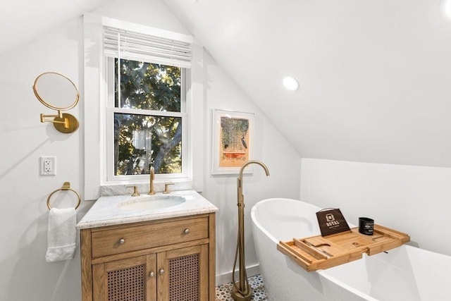 bathroom with vanity, a bath, and lofted ceiling