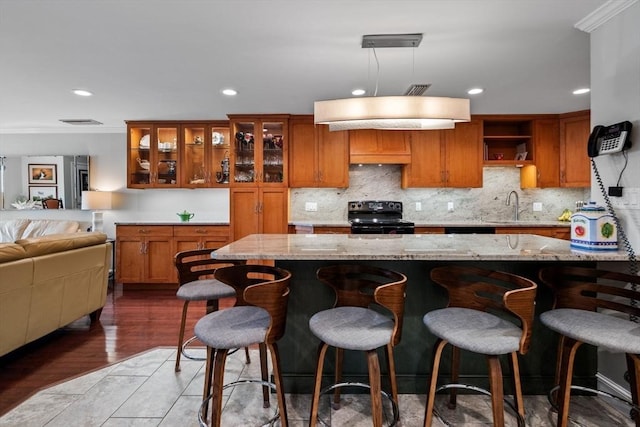150 Lynnway Unit 406, Lynn, MA 01902 - kitchen featuring black electric range oven, brown cabinetry, a breakfast bar area, tasteful backsplash, and recessed lighting