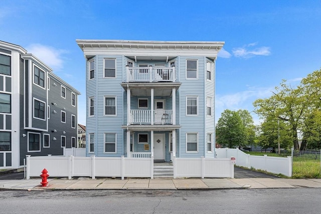 view of front facade featuring a balcony and a fenced front yard