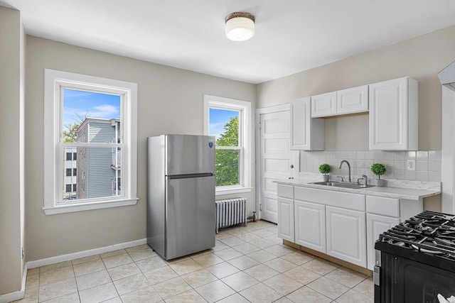 kitchen featuring radiator, stainless steel appliances, a sink, light countertops, and white cabinets