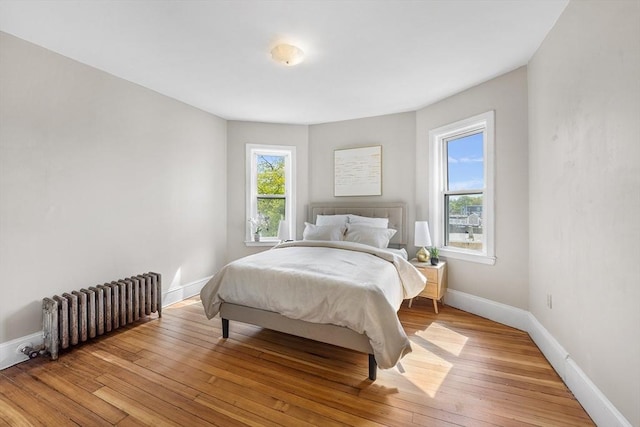 bedroom with radiator, baseboards, and light wood-style flooring