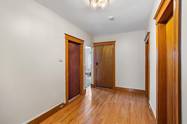 corridor featuring baseboards and light wood-style flooring
