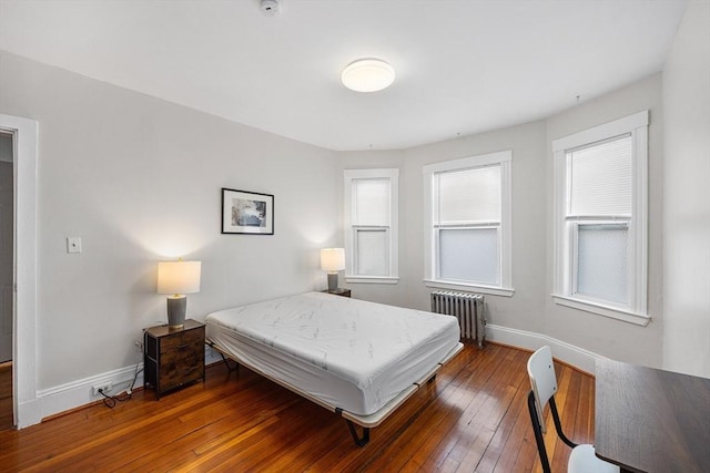 bedroom featuring radiator, baseboards, and hardwood / wood-style floors