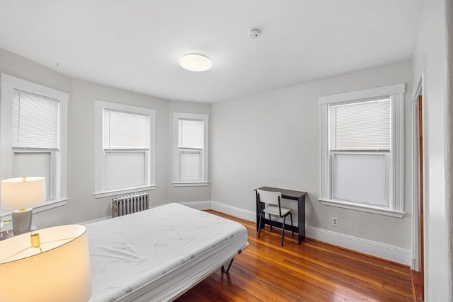 bedroom featuring radiator heating unit, baseboards, and hardwood / wood-style flooring