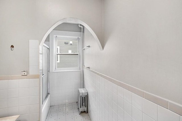full bath featuring radiator heating unit, tile walls, wainscoting, and tile patterned floors