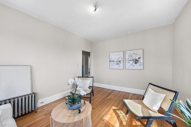 living area featuring radiator heating unit, wood-type flooring, and baseboards