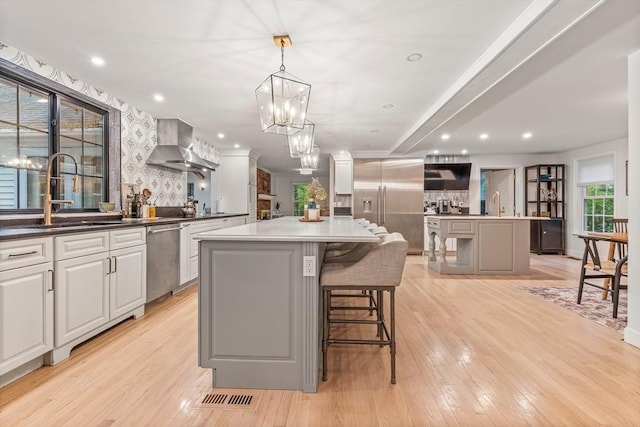 4 Rockwood Ln, Londonderry, NH 03053 - kitchen featuring a large island with sink, wall chimney exhaust hood, appliances with stainless steel finishes, a chandelier, and recessed lighting