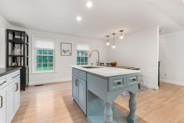 4 Rockwood Ln, Londonderry, NH 03053 - kitchen featuring a sink, light wood-style flooring, baseboards, pendant lighting, and a kitchen island with sink