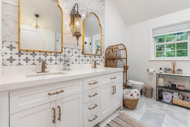4 Rockwood Ln, Londonderry, NH 03053 - bathroom featuring vaulted ceiling, double vanity, toilet, tasteful backsplash, and marble look tiles