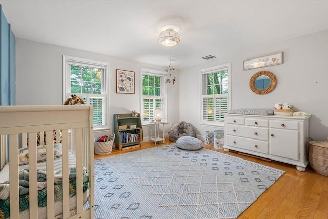 4 Rockwood Ln, Londonderry, NH 03053 - bedroom featuring multiple windows, light wood finished floors, and a crib