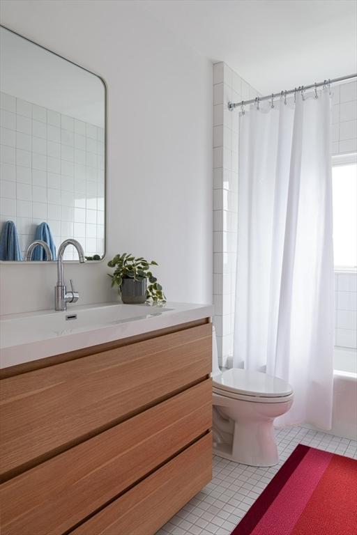 141 Fayerweather St, Cambridge, MA 02138 - bathroom featuring tile patterned floors, toilet, vanity, and shower / tub combo