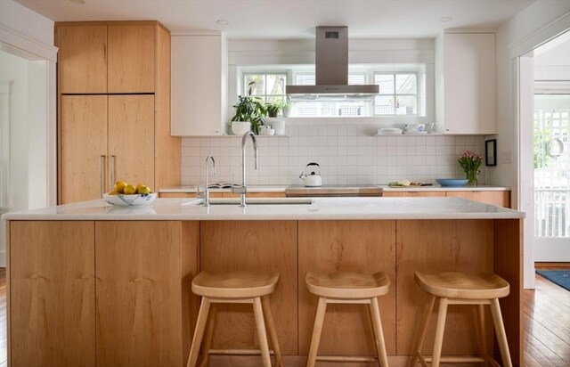 141 Fayerweather St, Cambridge, MA 02138 - kitchen with island range hood, light countertops, decorative backsplash, and a kitchen breakfast bar
