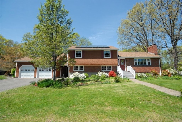 95 Bayberry Rd, Concord, MA 01742 - split level home featuring a front yard, solar panels, asphalt driveway, a chimney, and an attached garage