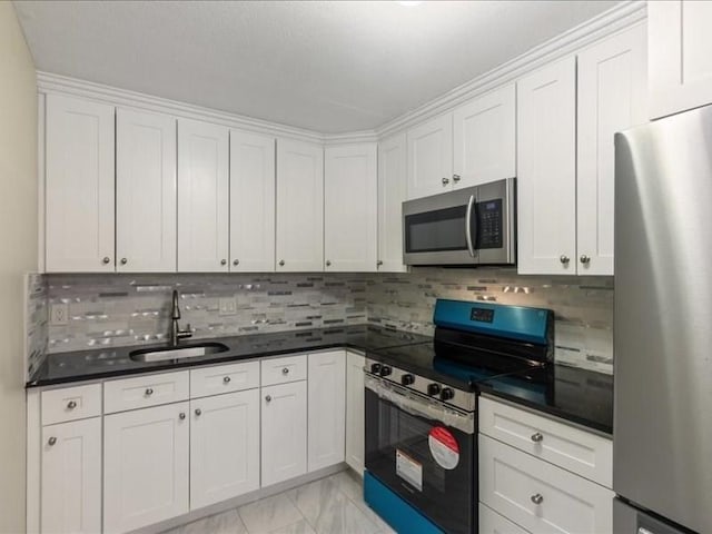 kitchen featuring appliances with stainless steel finishes, a sink, light marble finish flooring, and white cabinets