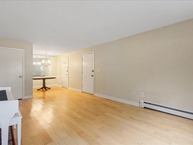 unfurnished living room featuring a chandelier, light wood-style floors, baseboards, and a baseboard radiator