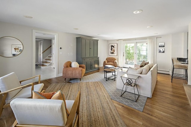 living room featuring recessed lighting, wood finished floors, a baseboard radiator, and stairs