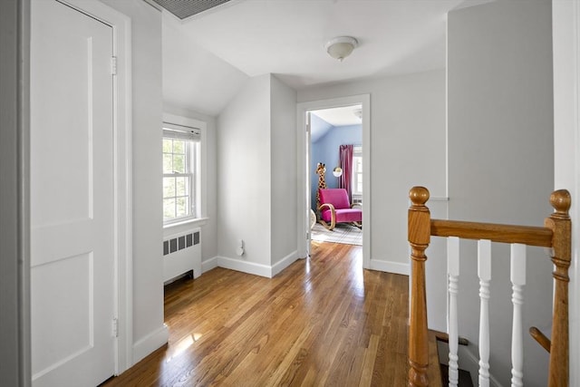 corridor featuring radiator, visible vents, wood finished floors, and baseboards