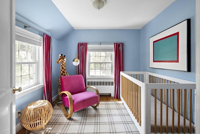 bedroom featuring wood finished floors, lofted ceiling, and radiator heating unit