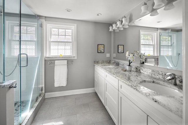 full bathroom featuring double vanity, baseboards, a shower stall, and a sink