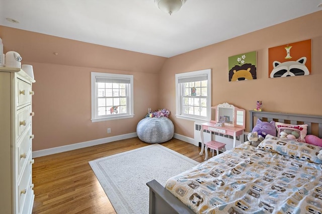 bedroom featuring baseboards, wood finished floors, and lofted ceiling