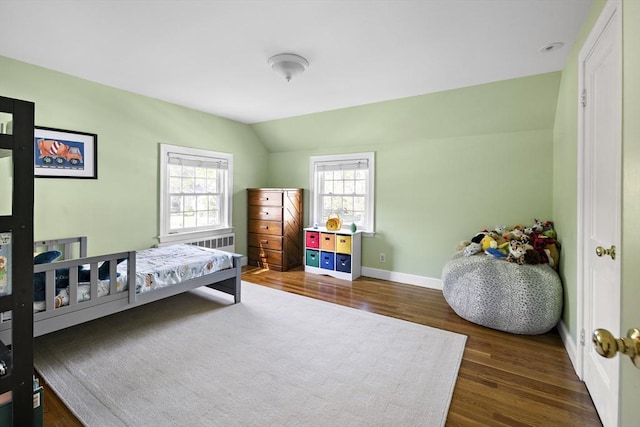 bedroom featuring dark wood-style flooring, lofted ceiling, and baseboards
