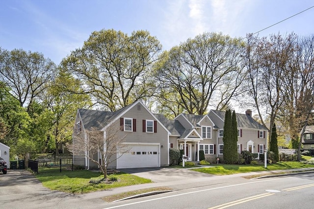 traditional-style home featuring an attached garage, a chimney, fence, a front yard, and driveway