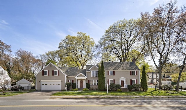 colonial house with a residential view, driveway, a garage, a front lawn, and a chimney